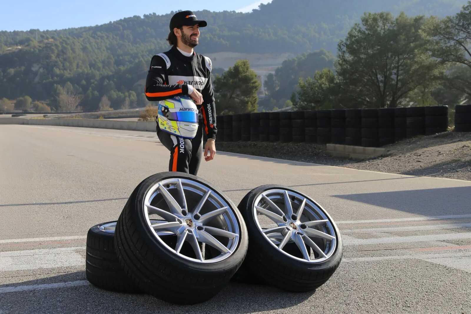Štyri pneumatiky Hankook Ventus S1 Evo Z na diskoch Porsche na okruhu, v pozadí jazdec v kombinéze Hankook s prilbou